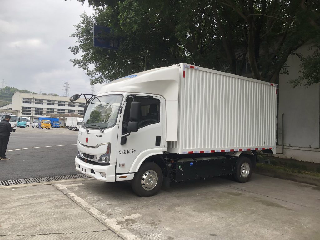 A white Qingling Isuzu M600 commercial box truck parked outdoors ready for fleet logistics.